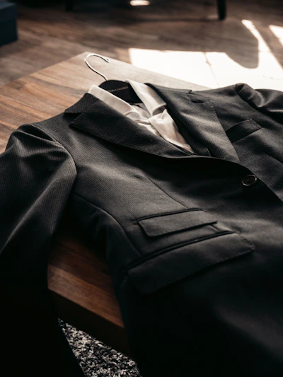 Close-up of a rich brown leather jacket laid out on a wooden table with soft natural light highlighting its texture.