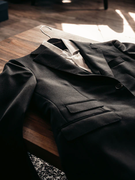 Close-up of a dark tailored jacket with sharp lapels on a minimalist black background