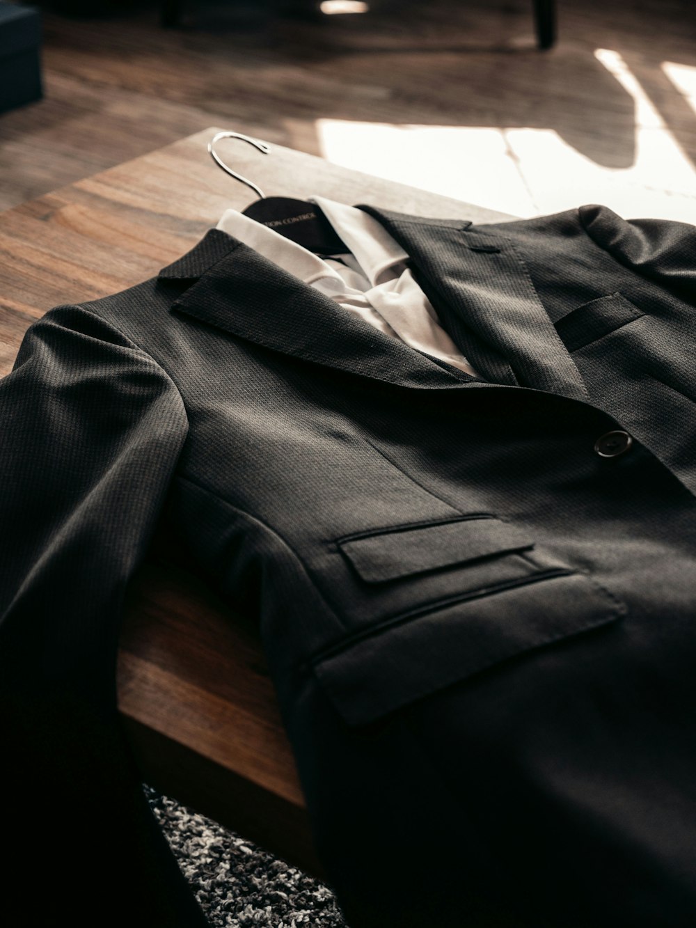 black suit jacket on brown wooden table