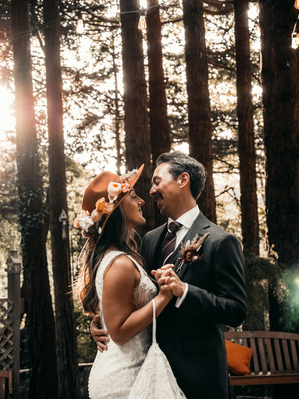 man in black suit jacket kissing woman in white sleeveless dress