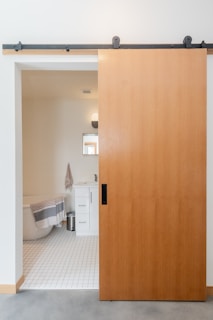 brown wooden door near white ceramic toilet bowl