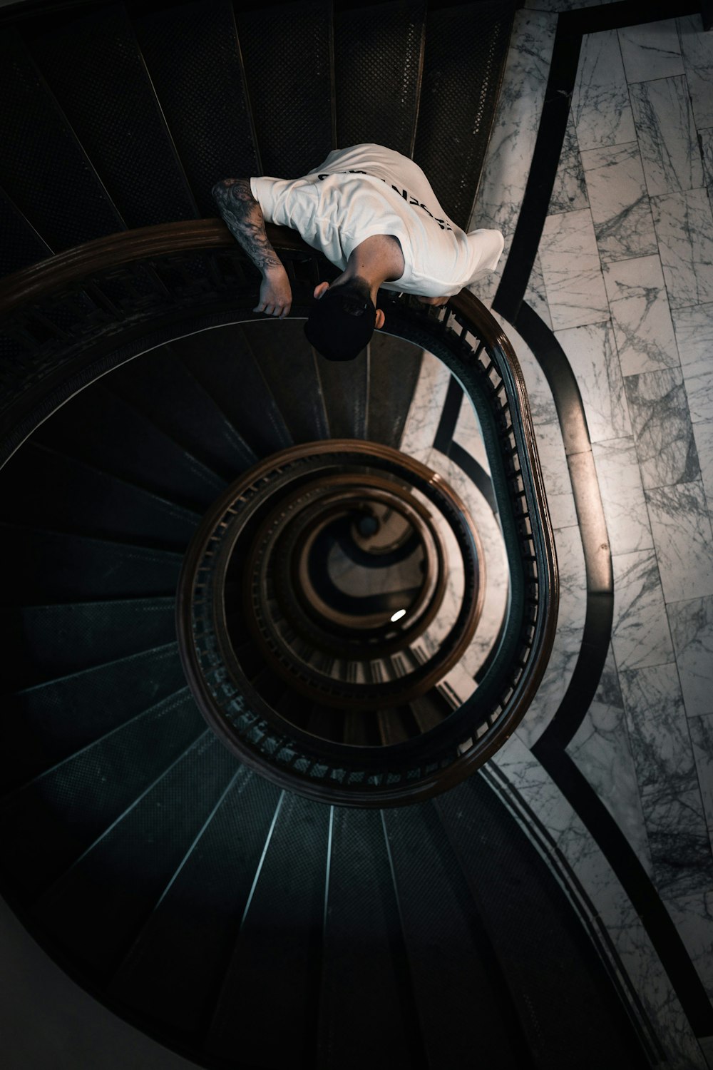 person in white long sleeve shirt and blue denim jeans walking on spiral staircase