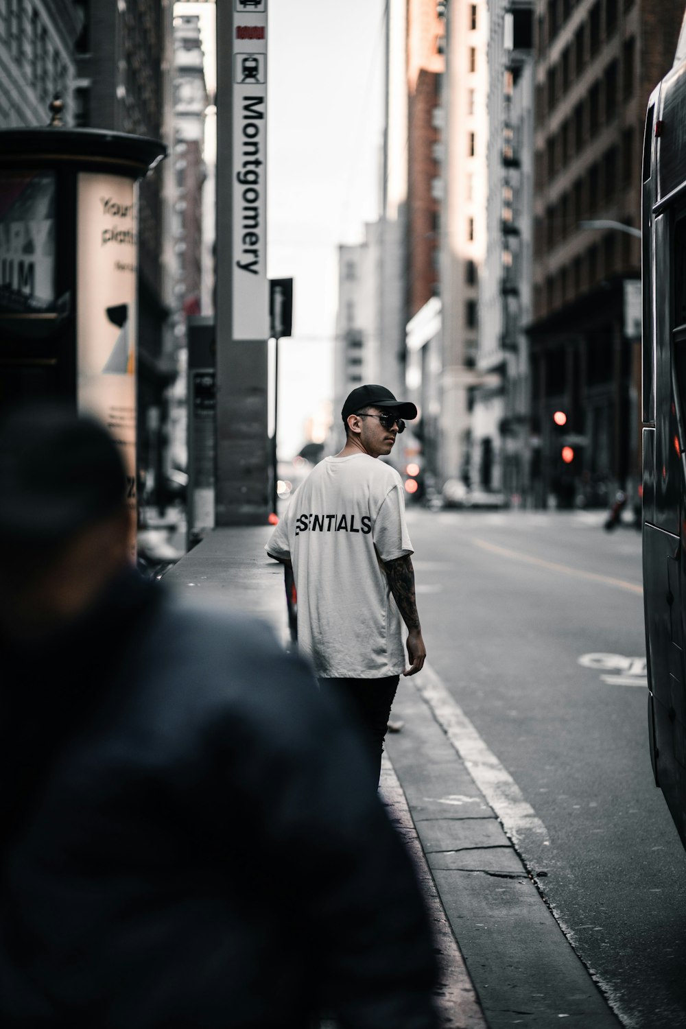 man in white t-shirt walking on sidewalk during daytime