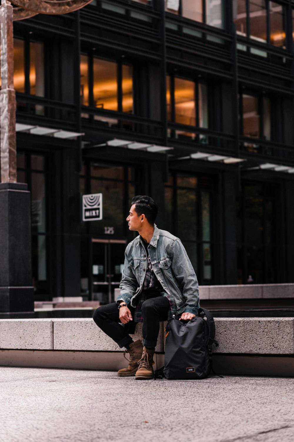 man in gray jacket and black pants sitting on gray concrete bench during daytime