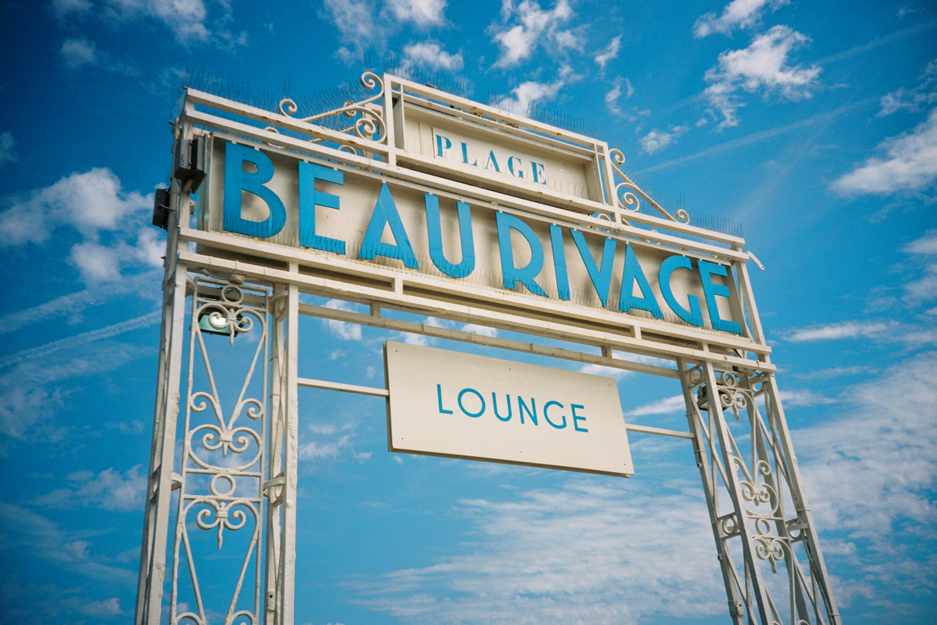 blue and white UNKs bar signage, The entrance to the Place Beau Rivage Lounge on the Promenade des Anglais in Nice, France. Shot on film.