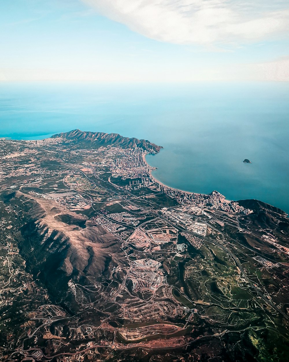 Vista aérea de montañas marrones y grises junto al cuerpo de agua durante el día