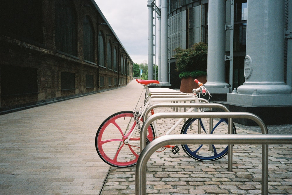 red city bike parked beside gray metal railings during daytime