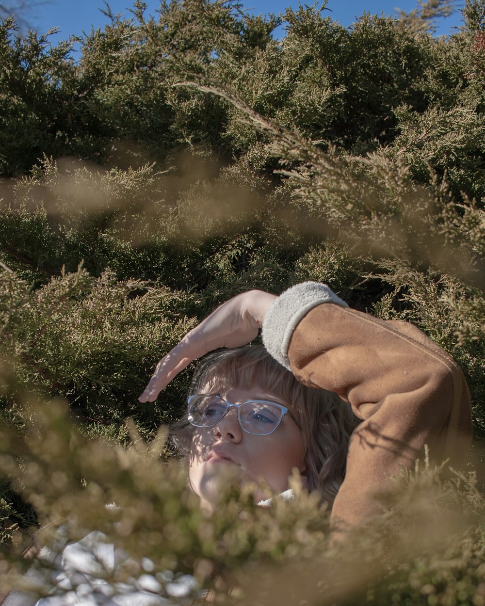 woman in brown jacket lying on green grass field during daytime