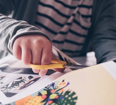 person in gray and black stripe long sleeve shirt holding yellow and silver scissors