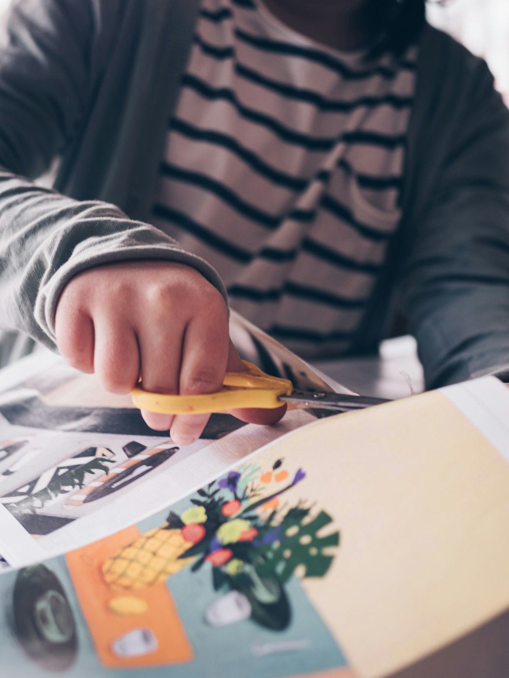 person in gray and black stripe long sleeve shirt holding yellow and silver scissors