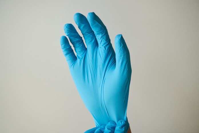 persons hand with blue nitrile gloves