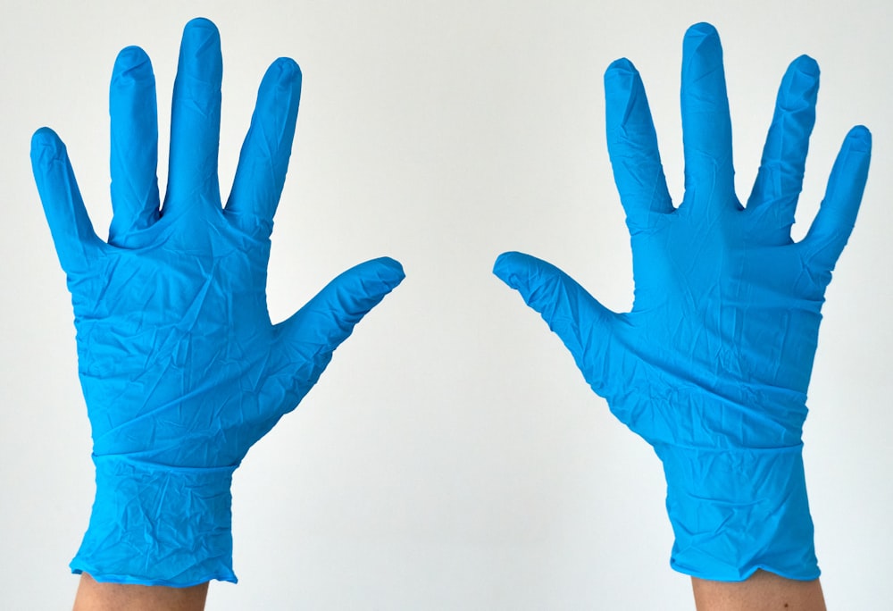 Person in blauen Handschuhen mit weißem Hintergrund