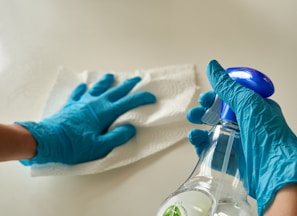 person holding blue textile near clear glass bottle