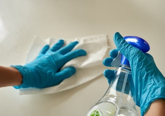 person holding blue textile near clear glass bottle