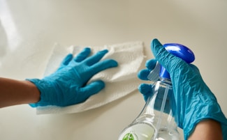 person holding blue textile near clear glass bottle