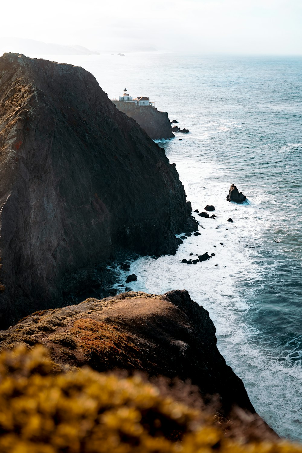 brown rocky mountain beside sea during daytime