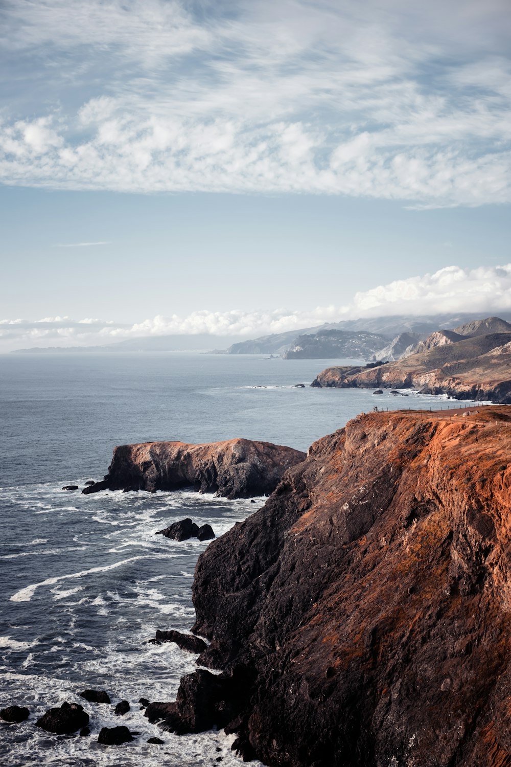 brown rock formation on sea under blue sky during daytime