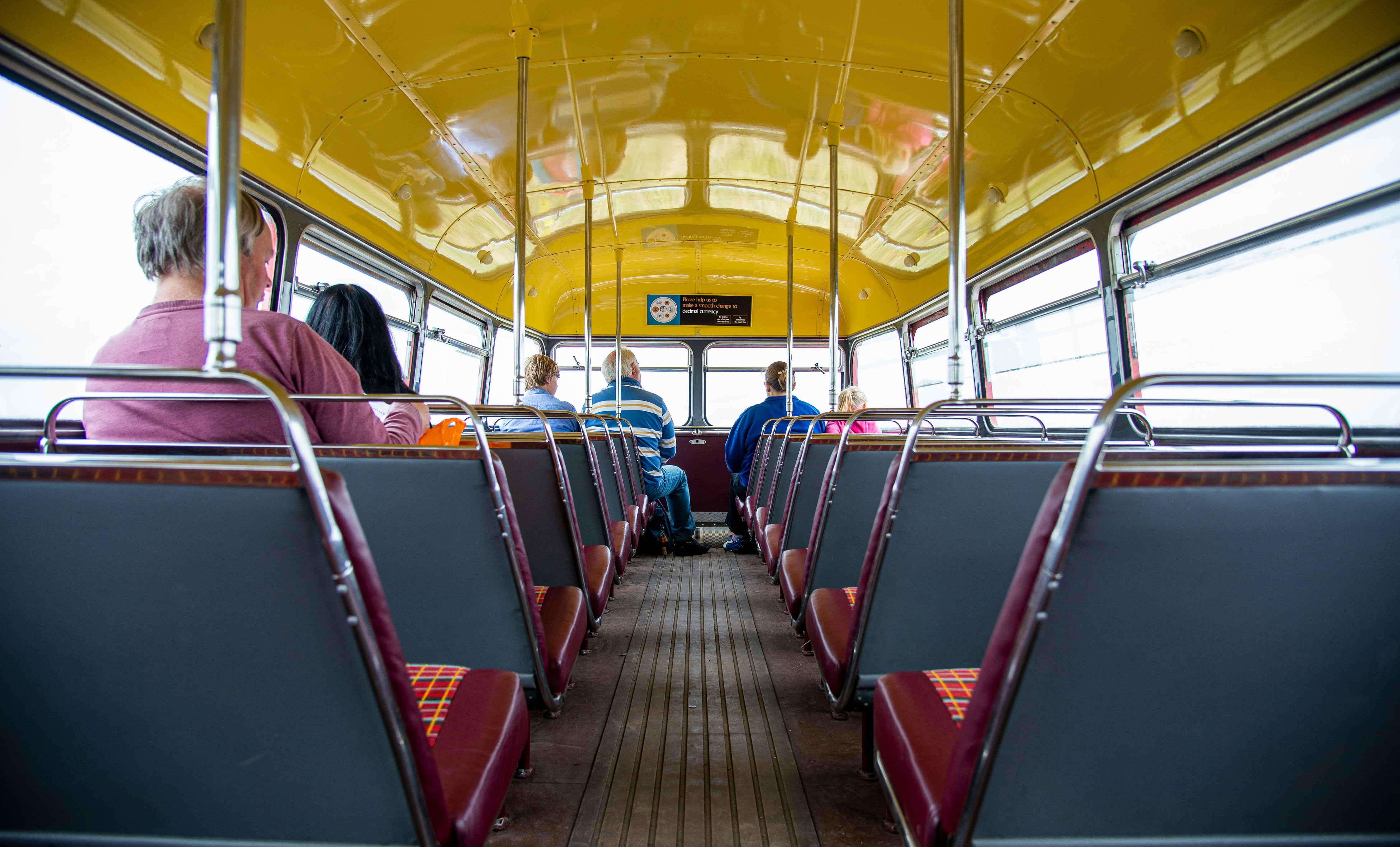 people sitting on red and blue bus seat, Sat on top deck of an old London routemaster bus, traveling over Salisbury Plain to the deserted Imber Village.