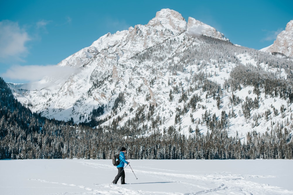 person in blue jacket and black pants walking on snow covered ground during daytime