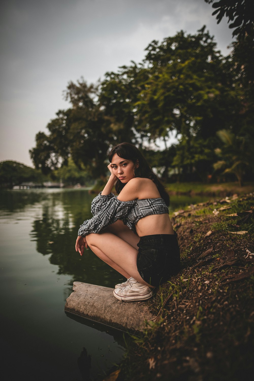 woman in black and white polka dot dress sitting on brown wooden log near body of near near near near