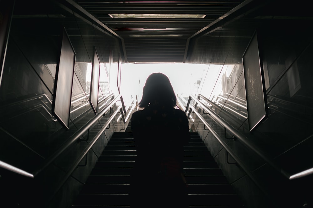 person in black hoodie standing on escalator