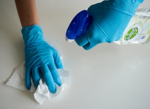 person in blue gloves holding white textile