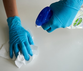 person in blue gloves holding white textile