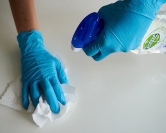 person in blue gloves holding white textile