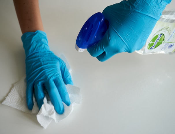 person in blue gloves holding white textile