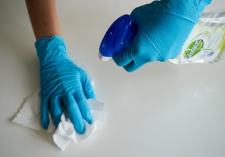 person in blue gloves holding white textile