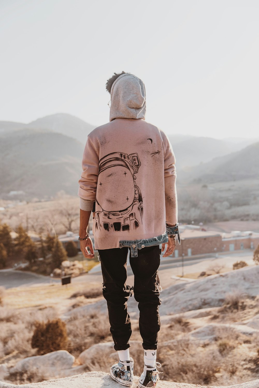 Hombre con suéter rosa y pantalones negros de pie sobre arena marrón durante el día