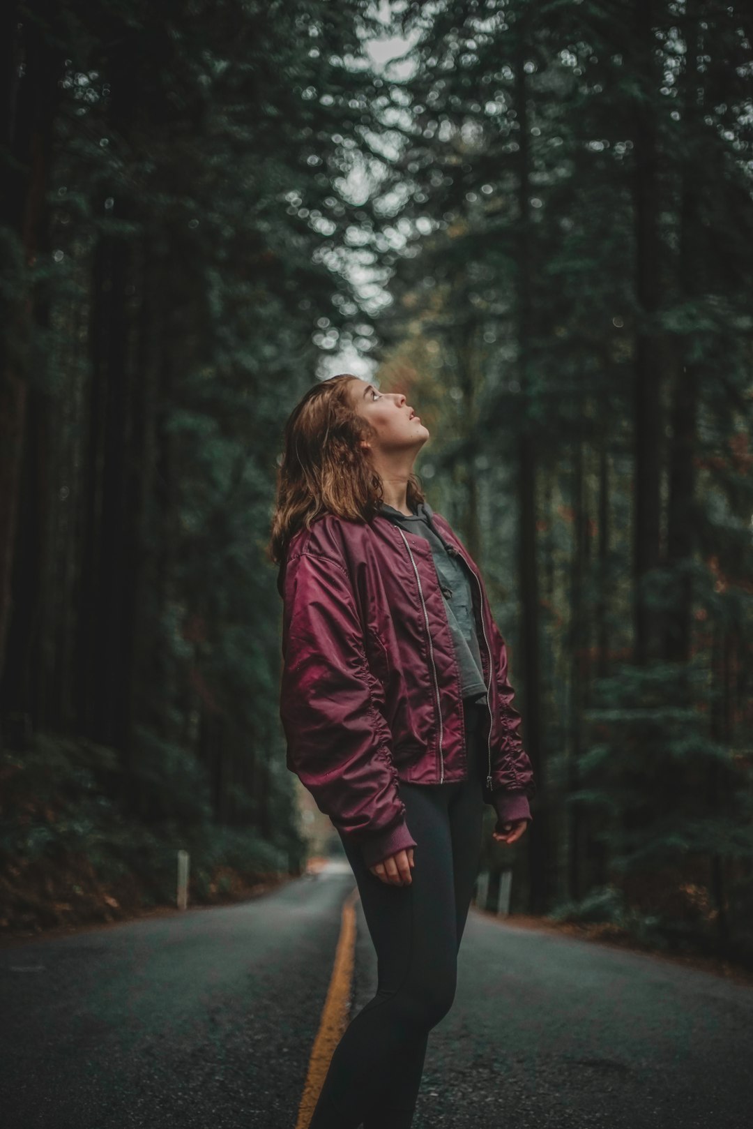woman in red jacket standing in the woods during daytime
