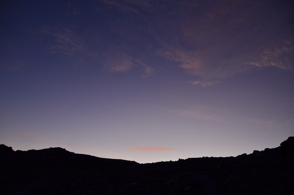 silhouette di montagna sotto il cielo blu durante il tramonto