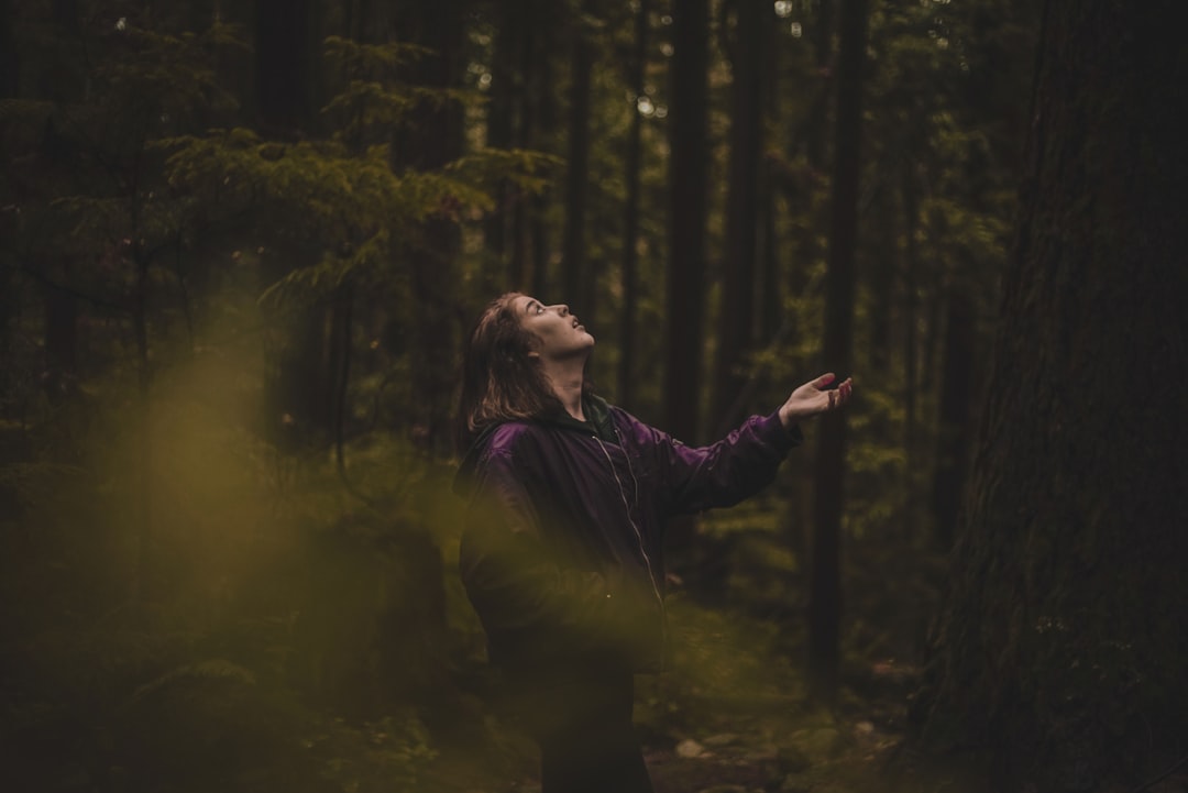woman in purple jacket standing in forest