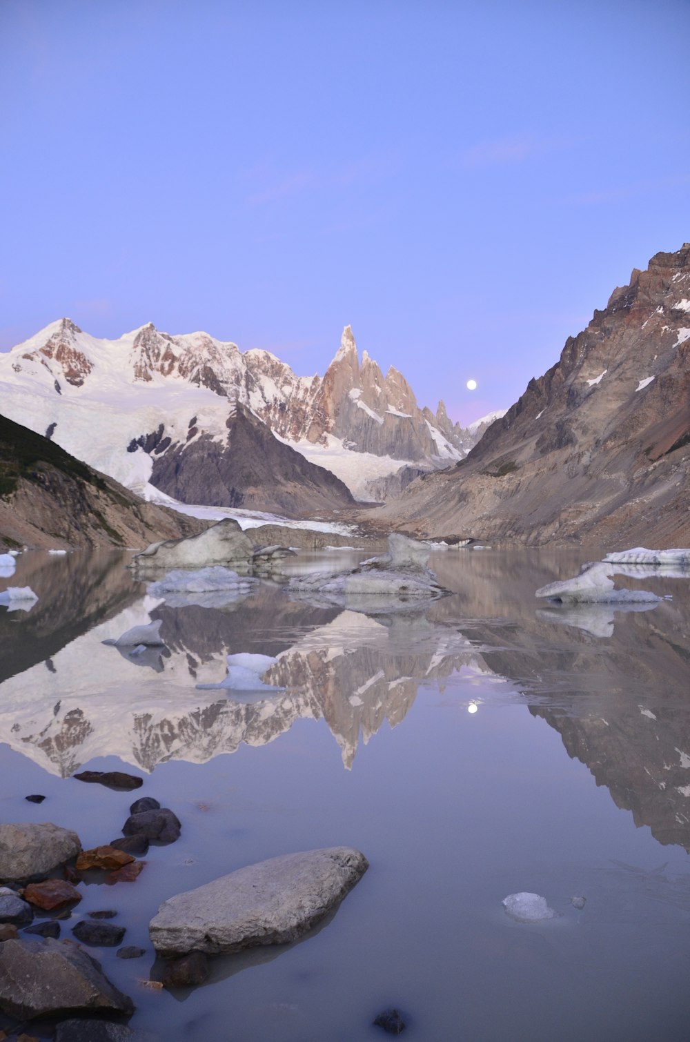 snow covered mountain near lake under blue sky during daytime