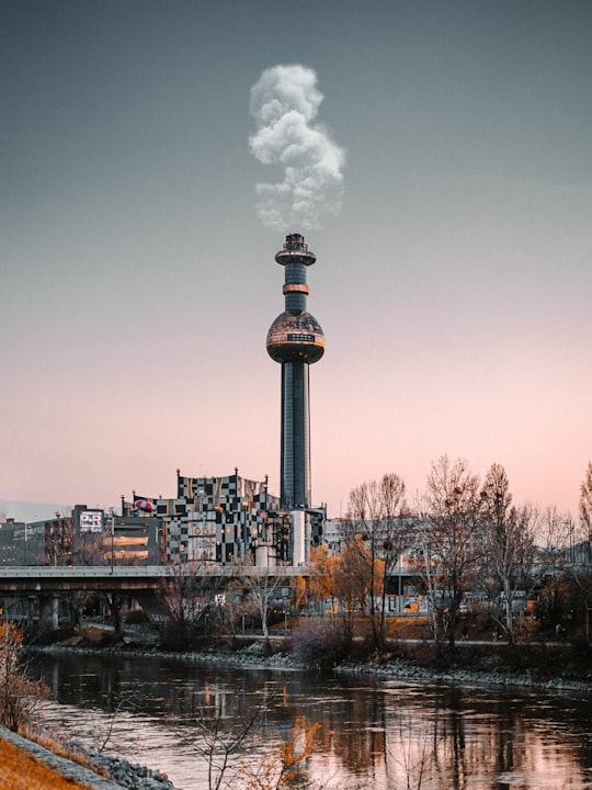 white and black tower near body of water during daytime in Spittelau Incineration Plant Austria