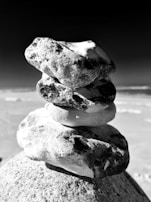 Close-up of smooth sea stones arranged in a balanced stack on the shore, representing harmony.