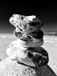 Close-up of smooth sea stones arranged in a balanced stack on the shore, representing harmony.