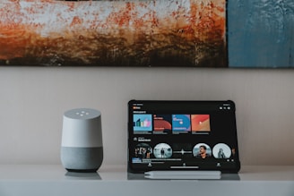 black ipad beside white portable speaker