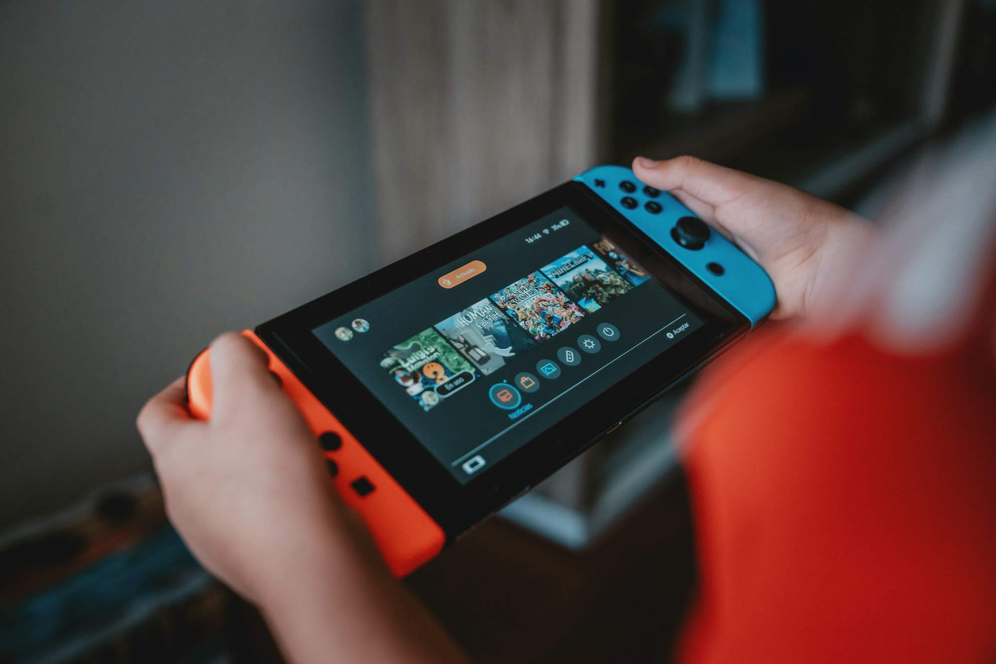 A Nintendo Switch console, showing the main menu, with red and blue remotes attached.
