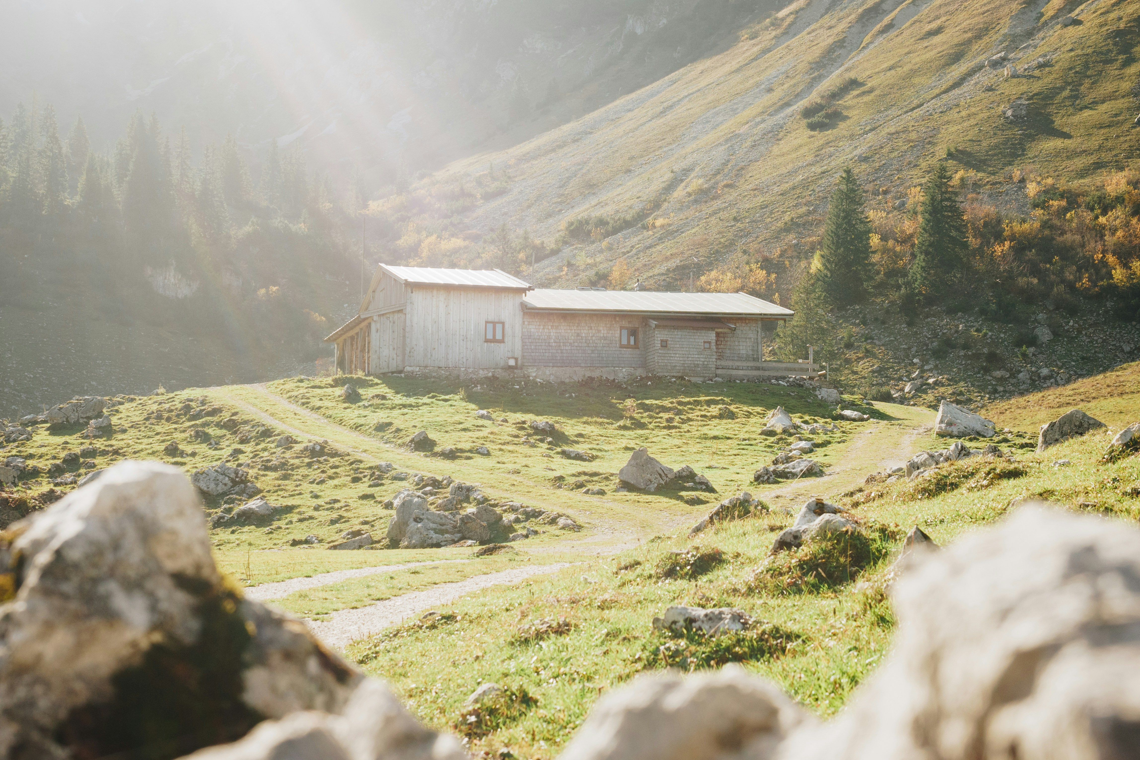 Brown wooden house on green grass field near mountain during daytime ...