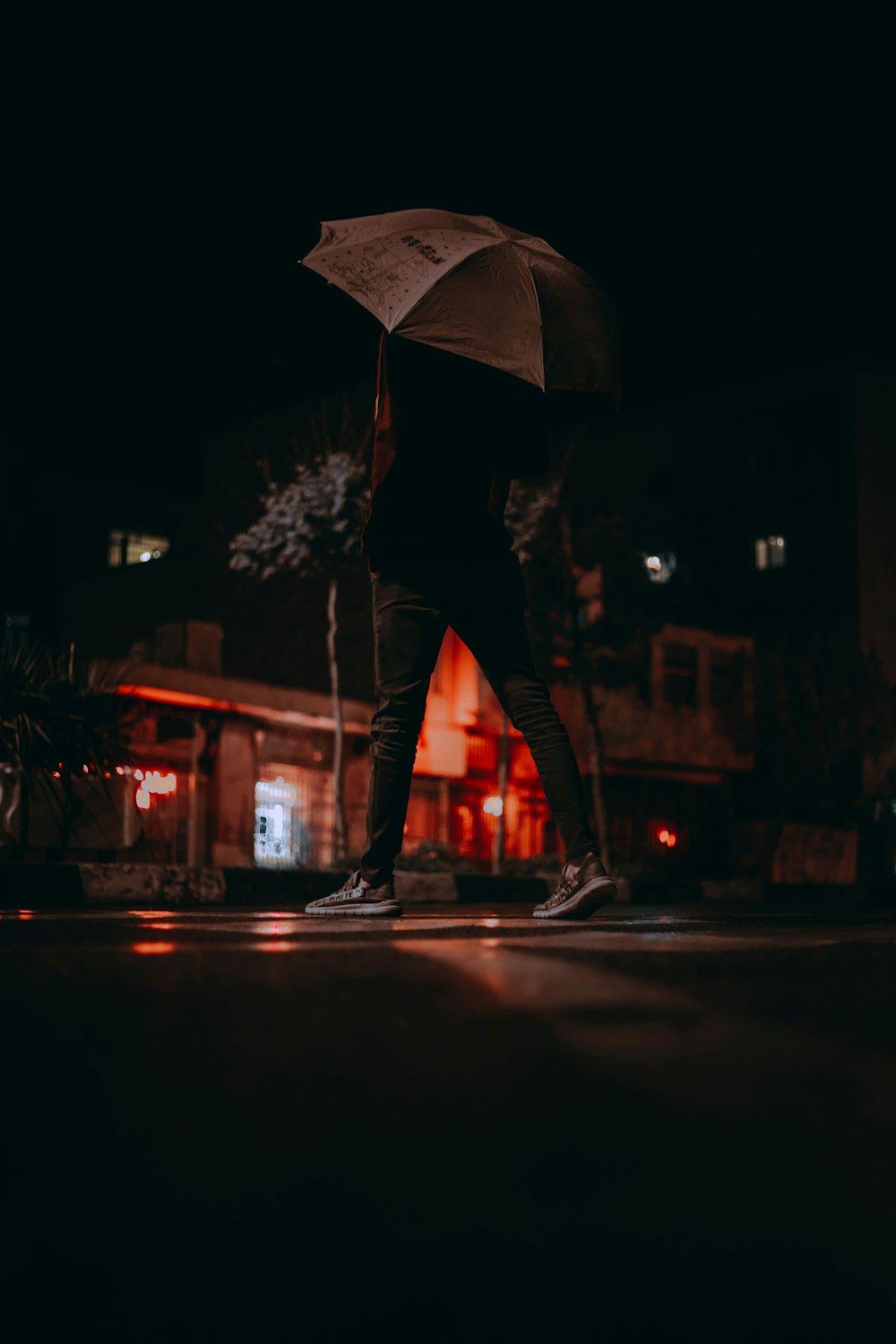 woman in black jacket and black pants holding umbrella standing on road during night time