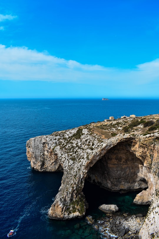 brown and green rock formation on sea under blue sky during daytime in Blue Wall and Grotto Viewpoint Malta