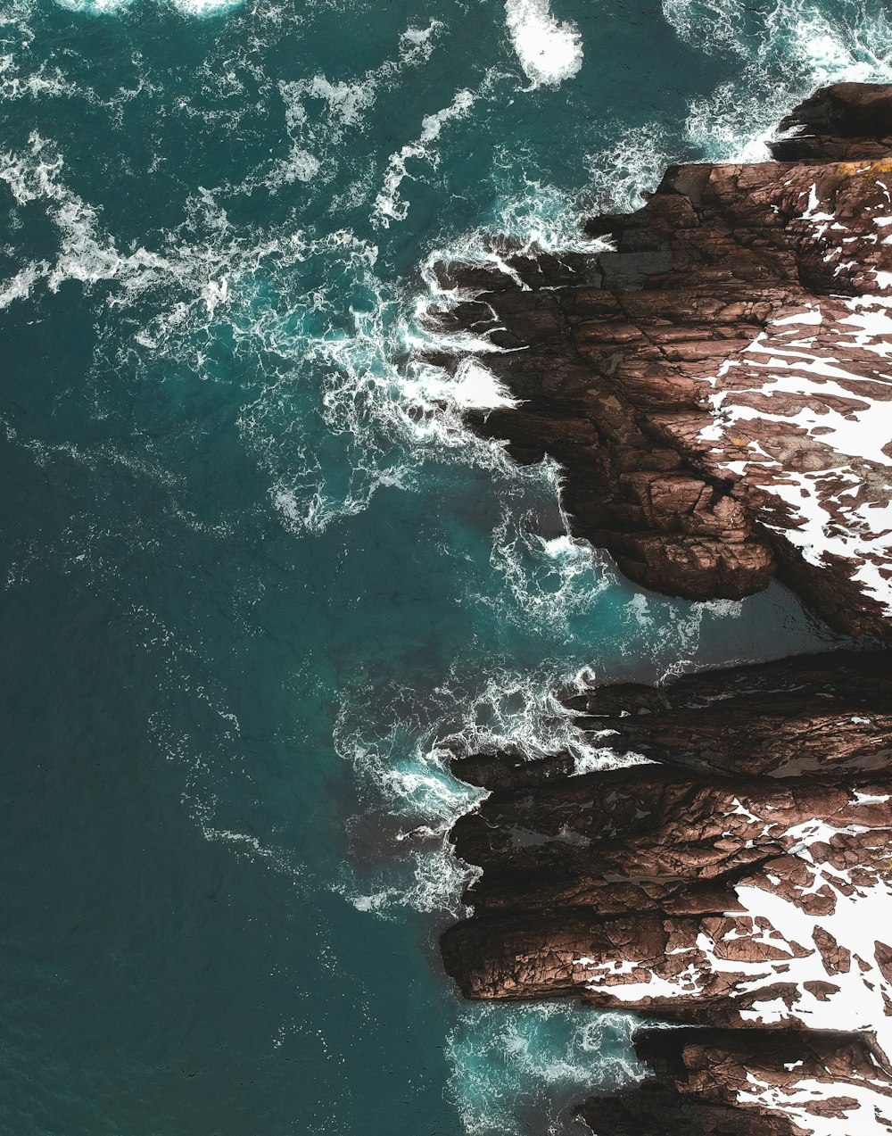 brown rock formation beside body of water during daytime