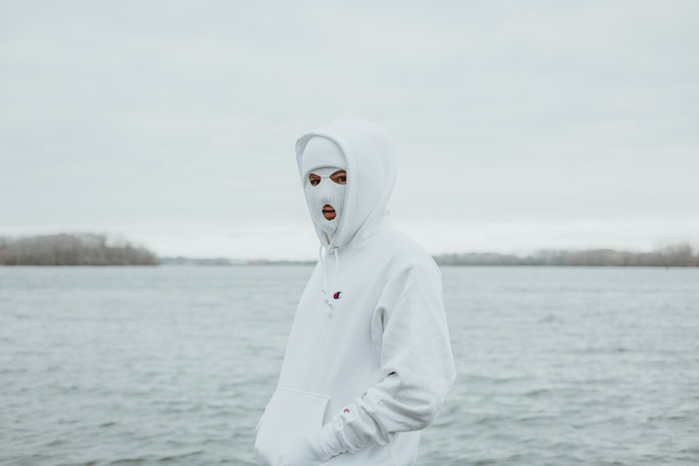 person in white hoodie standing near body of water during daytime