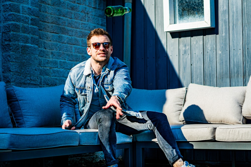 man in blue denim jacket and black pants sitting on bench