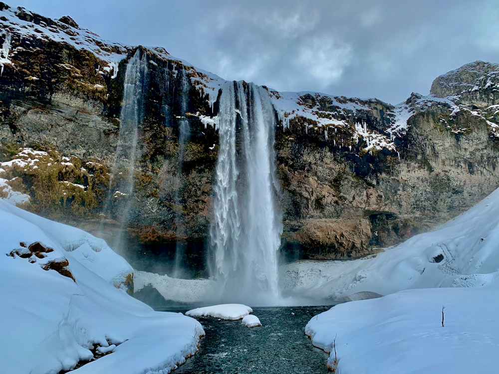 waterfalls in the middle of snow covered mountain