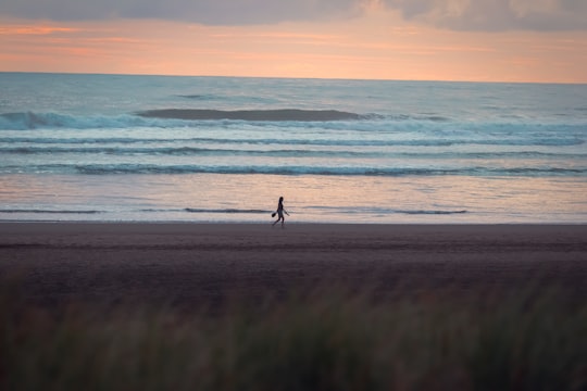 person walking on beach during sunset in Piha New Zealand