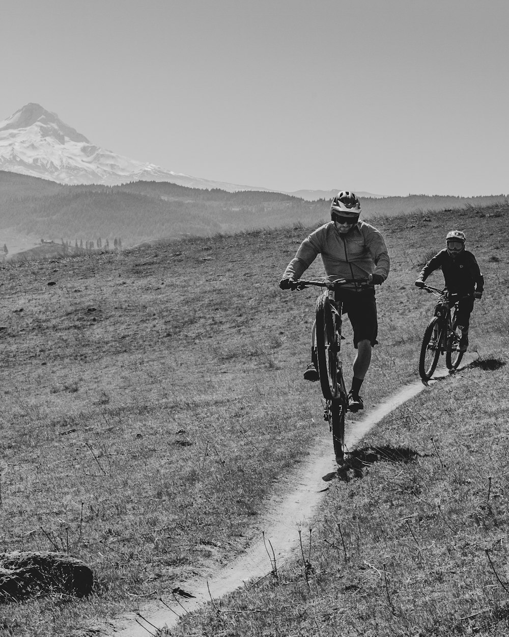 grayscale photo of 2 men riding bicycle on road