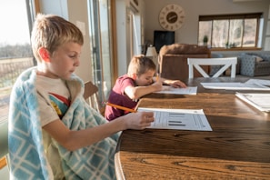 boy in white green and blue plaid button up shirt writing on white paper